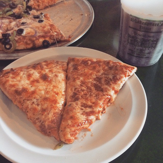 Two slices of Shakespeare's pizza next to their iconic cup